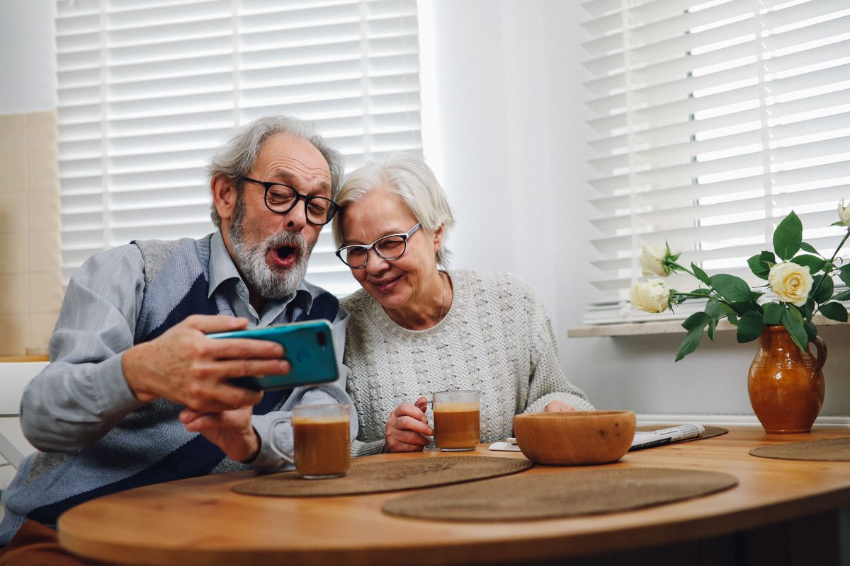 Grandparents watching a replay on a phone at the kitchen table